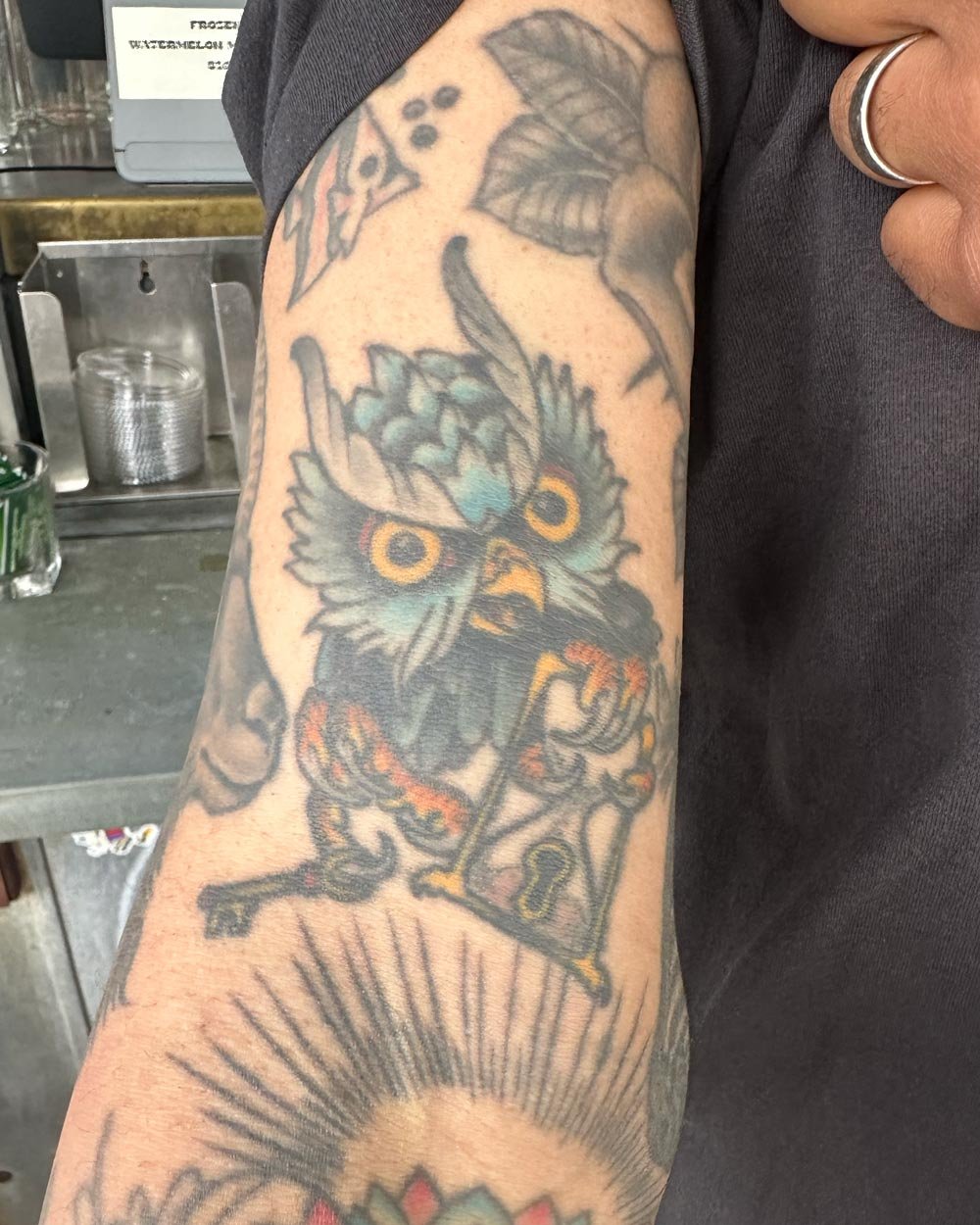 Healed owl tattoo on an upper inner arm.