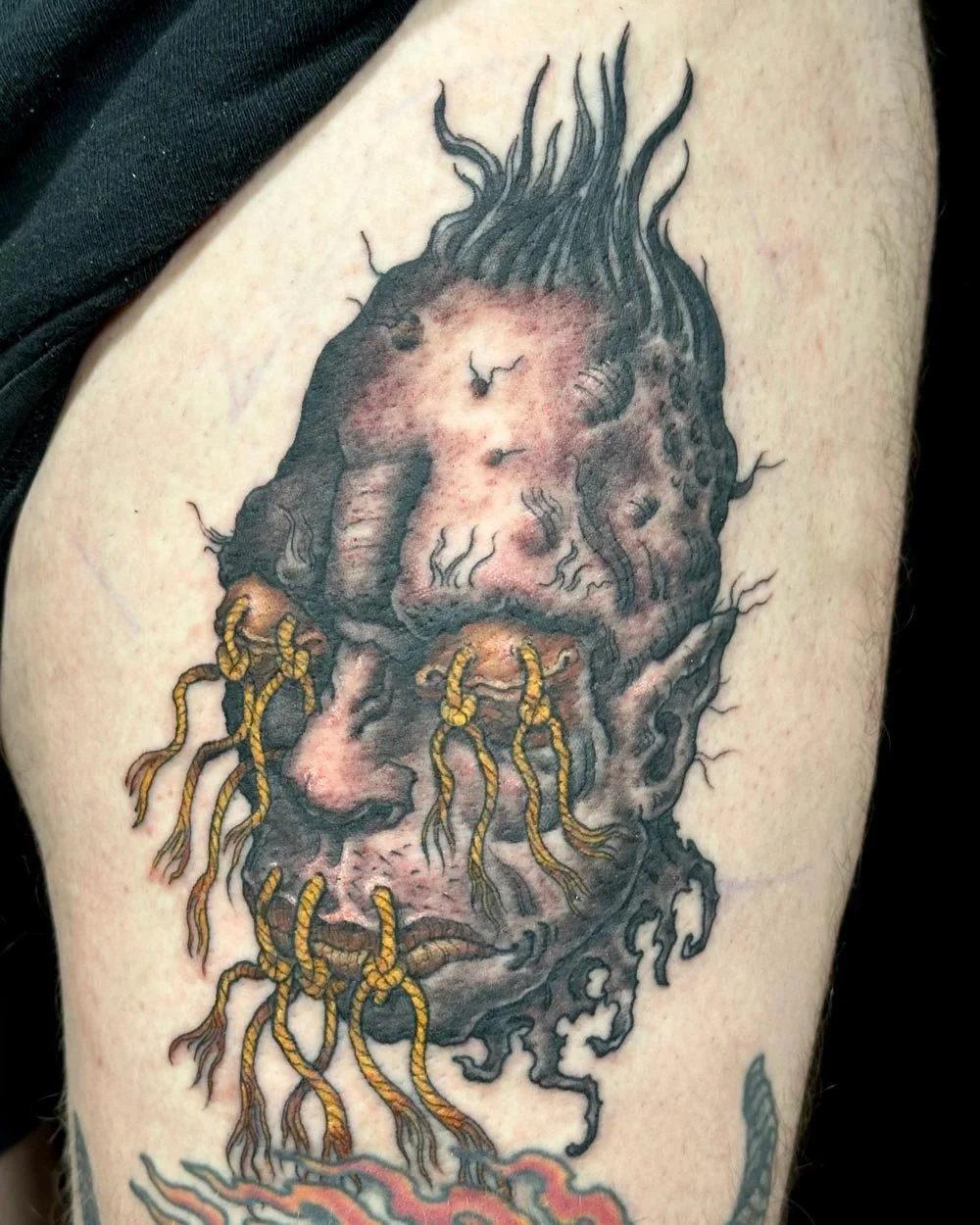 Shruken head tattoo on a thigh by John Reardon.