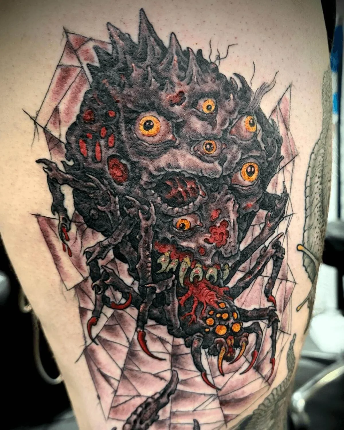 Horror color tattoo of a sci-fi spider with many eyes and web in the background.