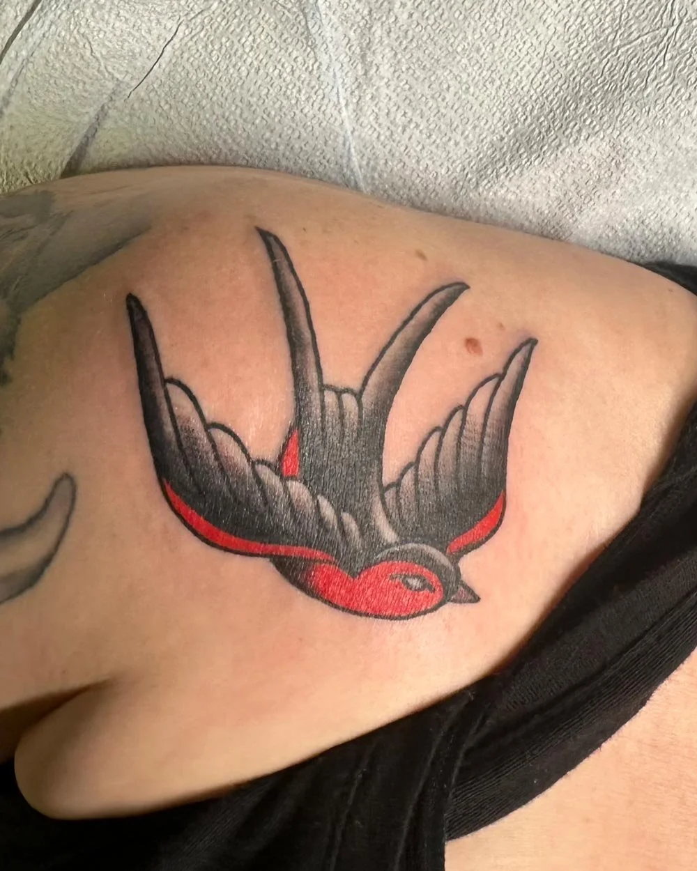 Matching color tattoos on the collarbones of traditional red sparrows.