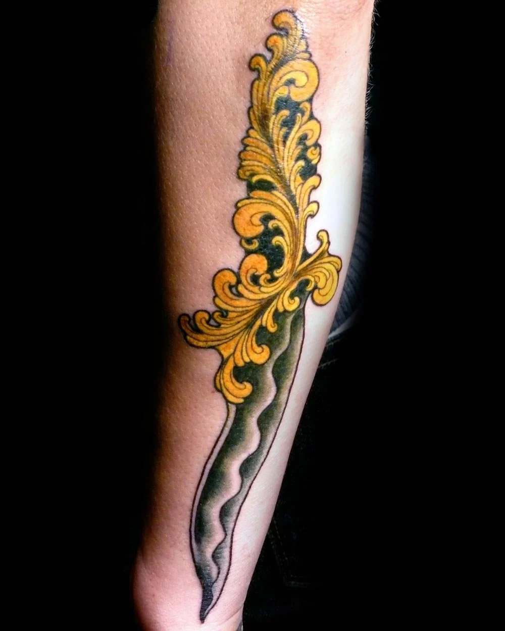 Gold dagged tattoo on an arm done by artist John Reardon.