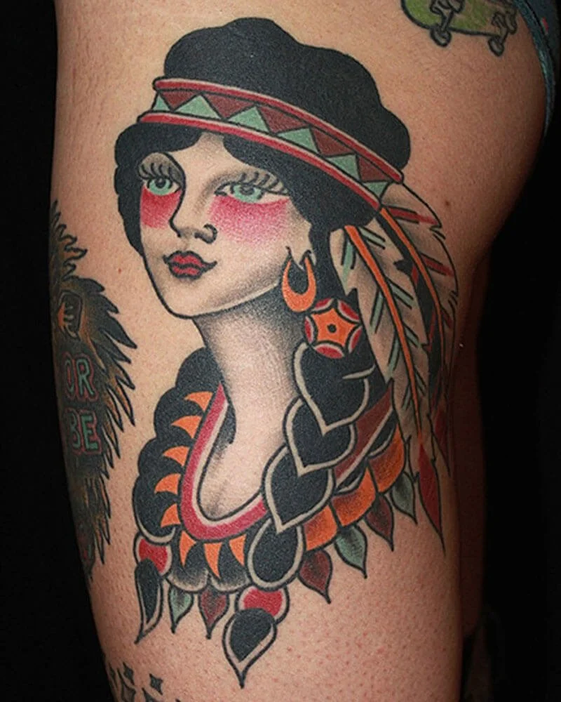 Color tattoo of a traditional woman portrait wearing a headband and jewelry.