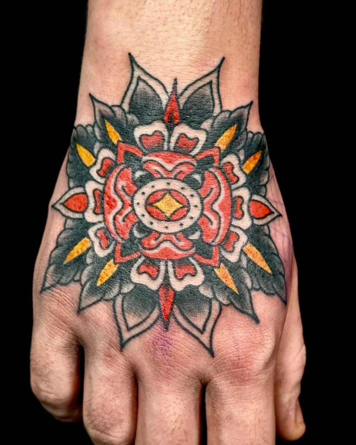 Traditional rose tattoo on the top of a hand.