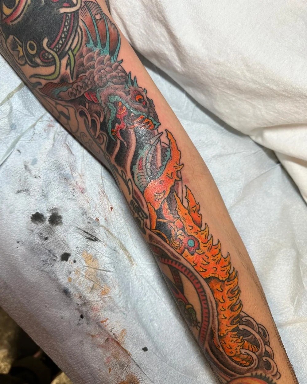 Custom drawn-on color tattoo of a fish and lobster fighting in water.