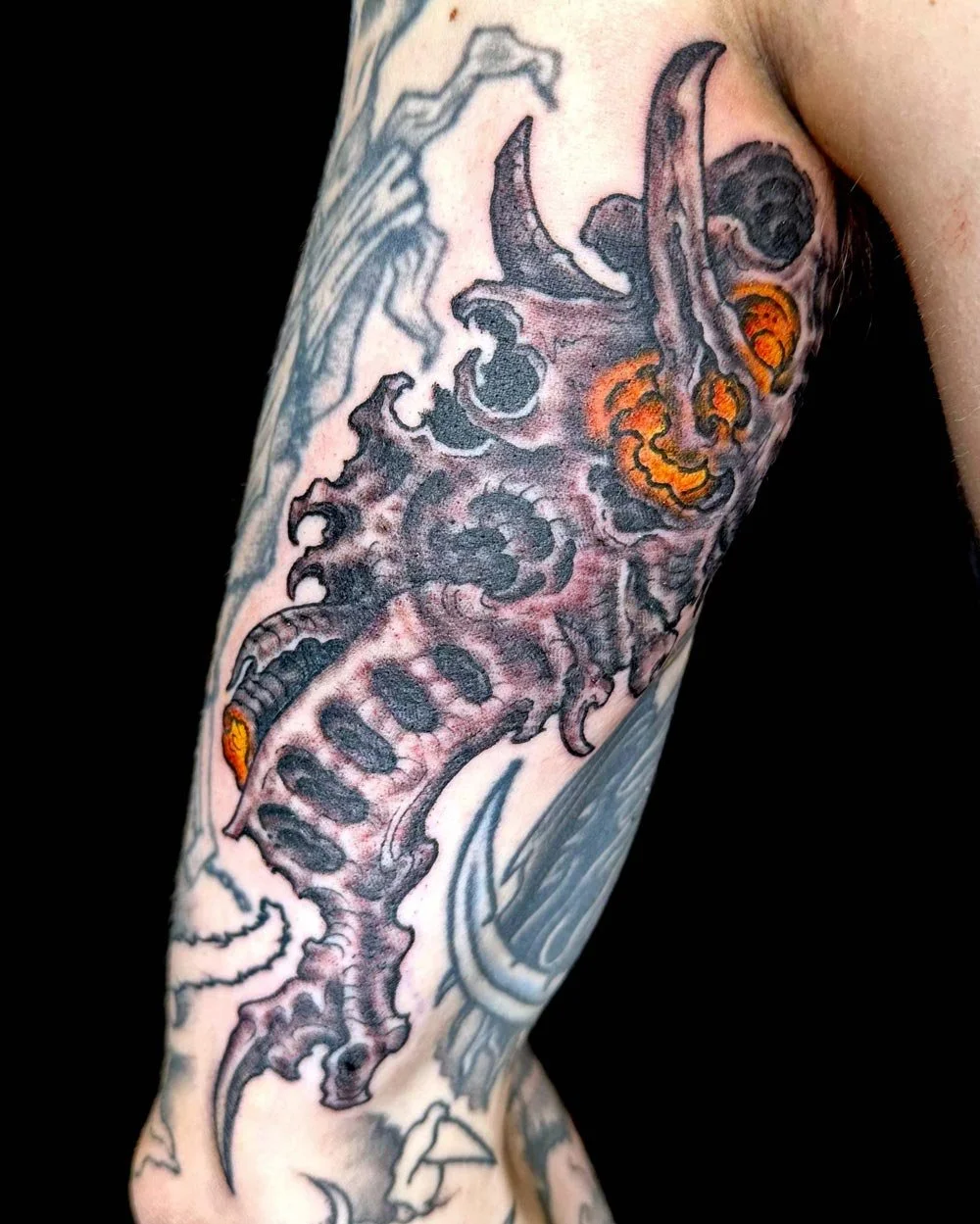 Drawn-on tattoo of a biomech skull with a burst of colors.