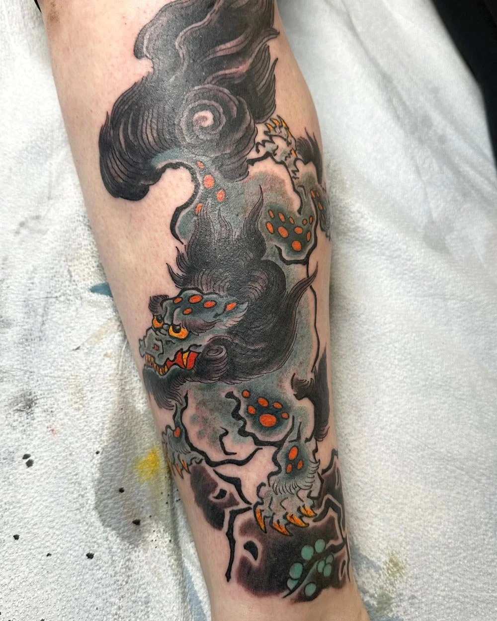 Color tattoo by John Reardon of a blue food dog on a leg.