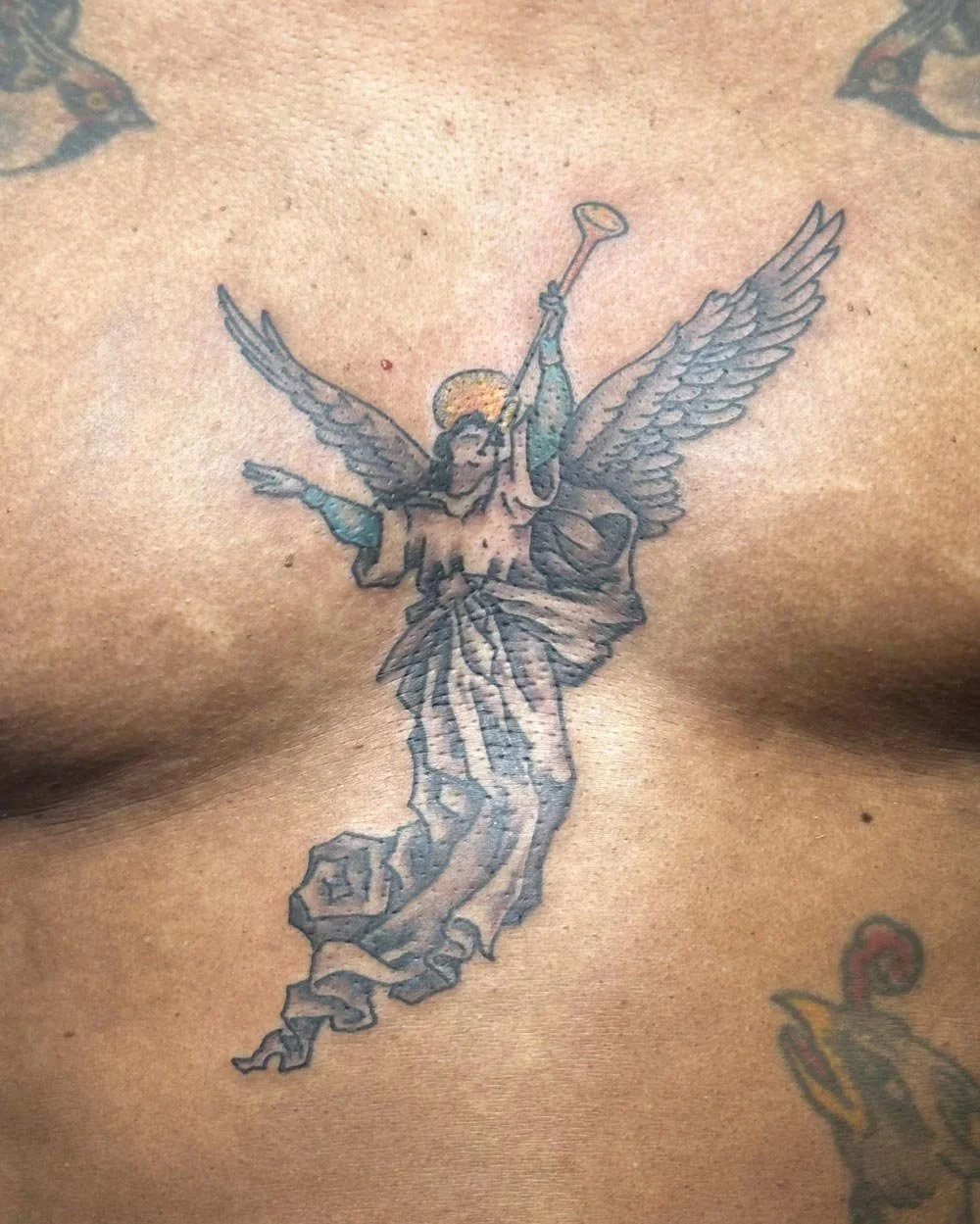 Chest color tattoo of an angel blowing a trumpet.