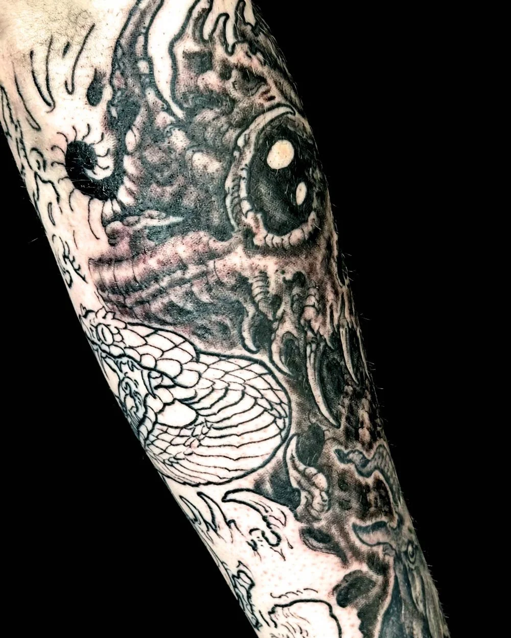 Back of the arm view of a black and grey John Reardon biomech drawn on tattoo on upper-arm.