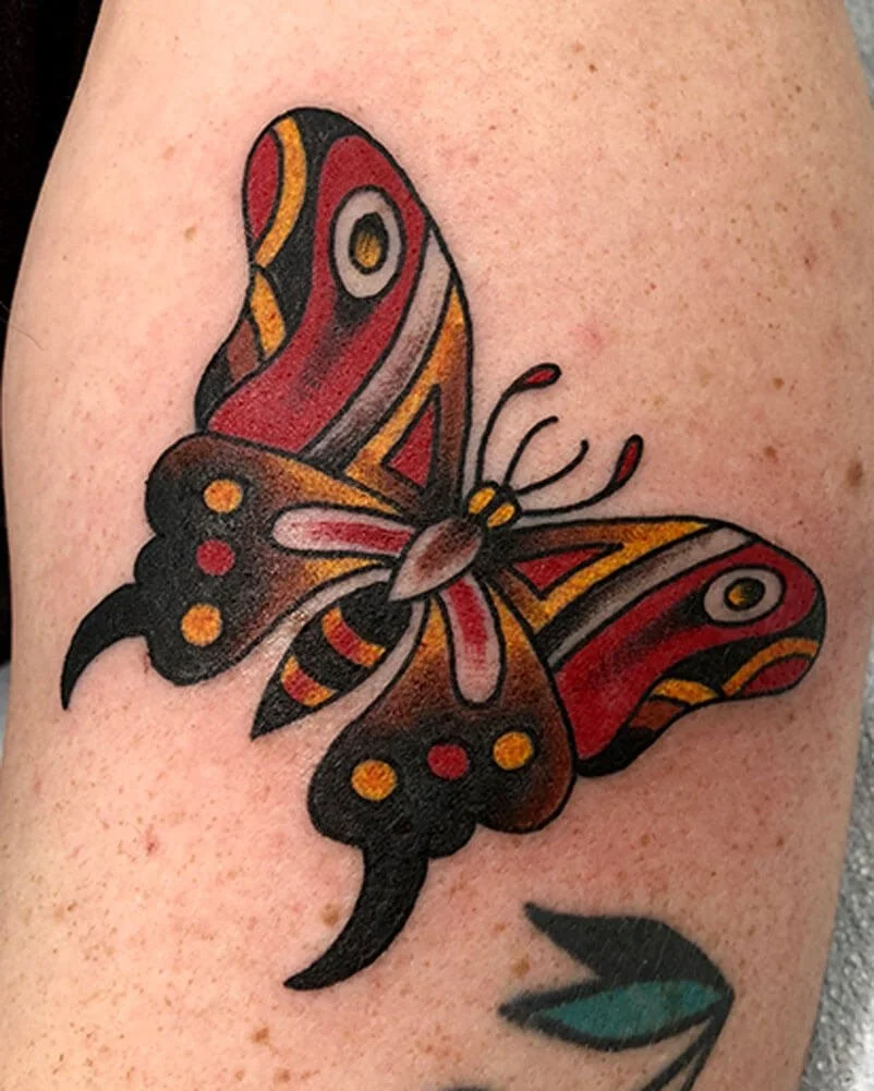 Red, yellow, and brown traditional butterfly tattoo.