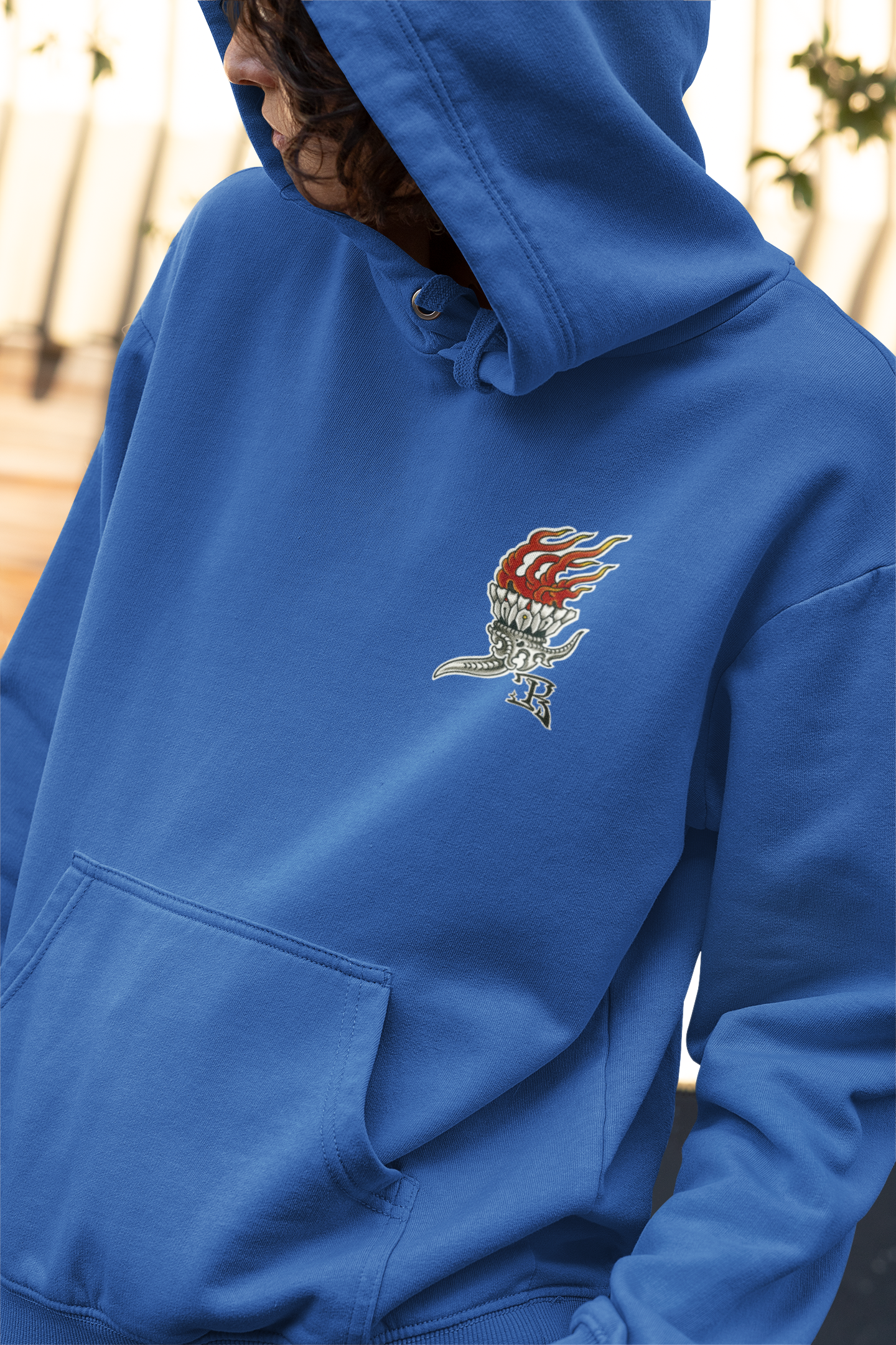 Close up of the front logo on royal-blue Greenpoint Tattoo Co hoodie on a model.