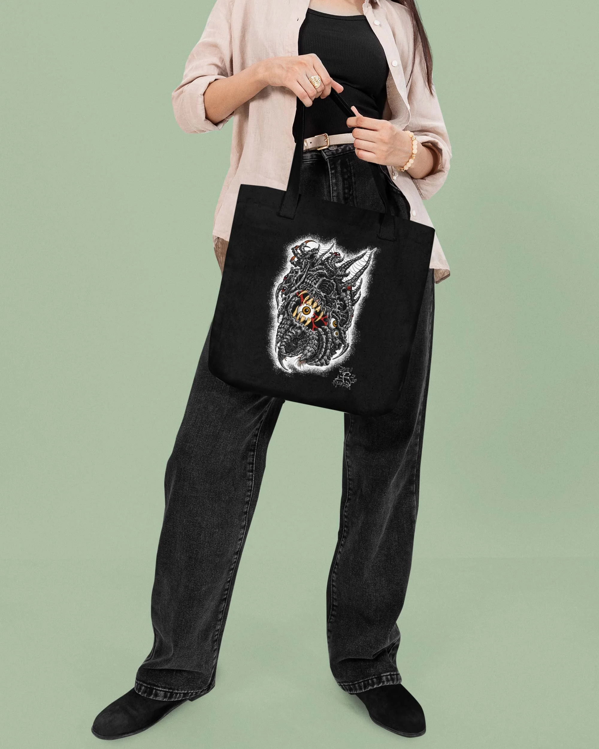 Model holding a tote bag with John Reardon design of biomech skull and eyeballs.