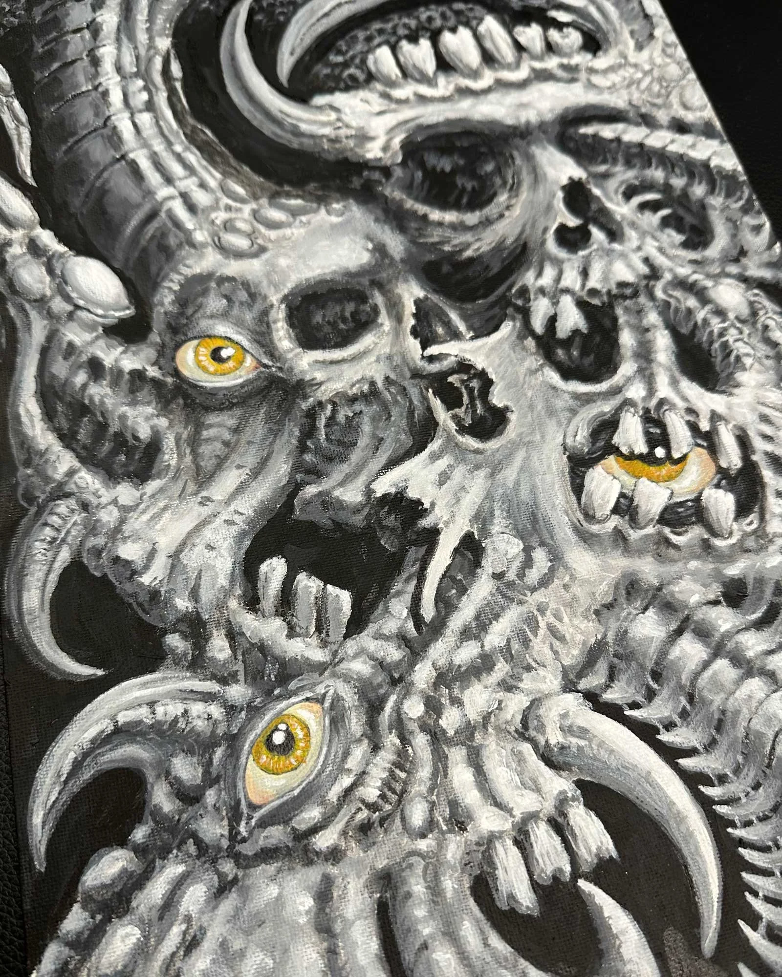 Close-up view of an original John Reardon bio-mechanical skull painting in black and grey paint with yellow highlights.
