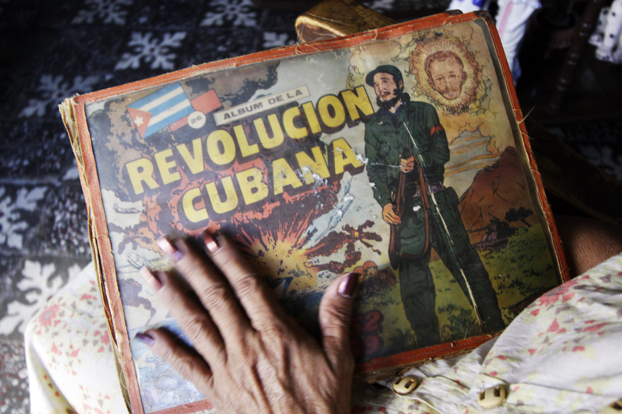  Daisy Payas Morillo, 61, president of a  revolutionary neighbourhood watch organisation CDR, gently touches an album with Revolution stickers that bears the cover image of ailing Cuban Revolution leader Fidel Castro, 2008. 