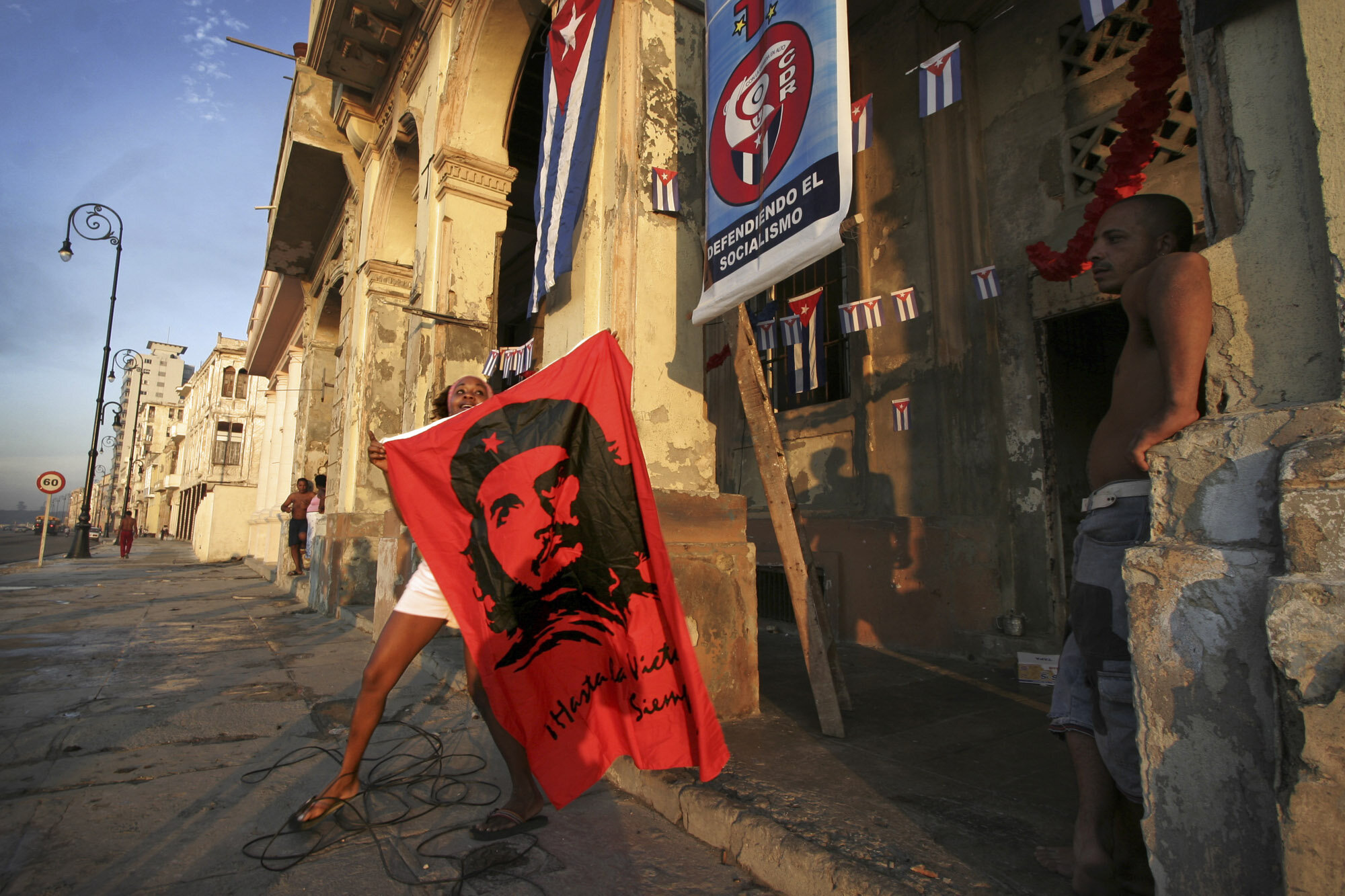  A Cuban woman carries a Che Guevara flag as people are preparing for the CDr anniversary, Havana's Malecon, 2005.          
