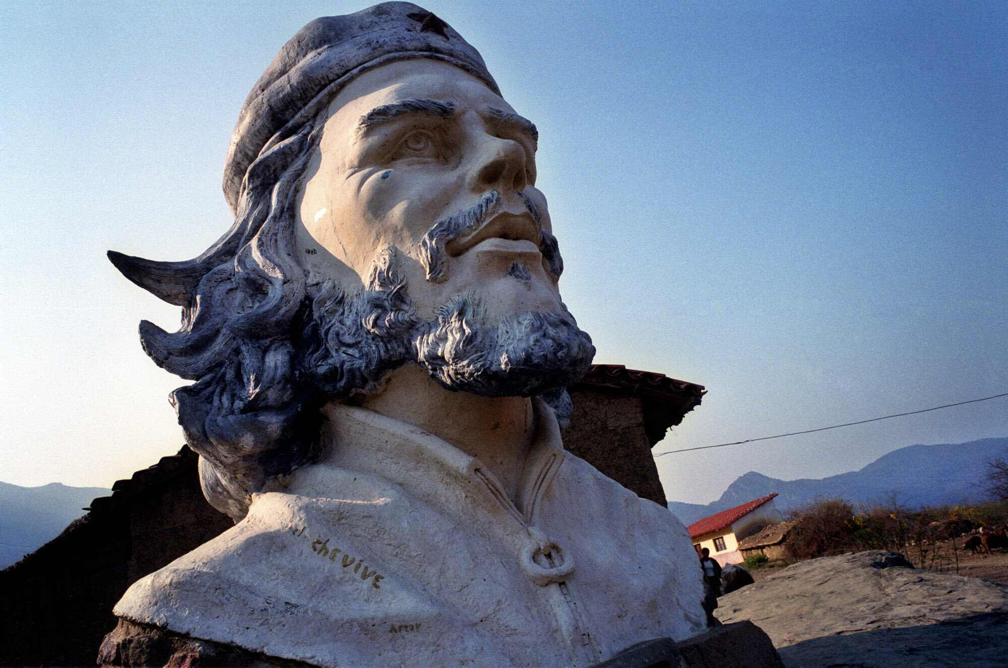  Che Guevara bust in La Higuera and the school where he was shot on Oct 9, 1967, in the background. 