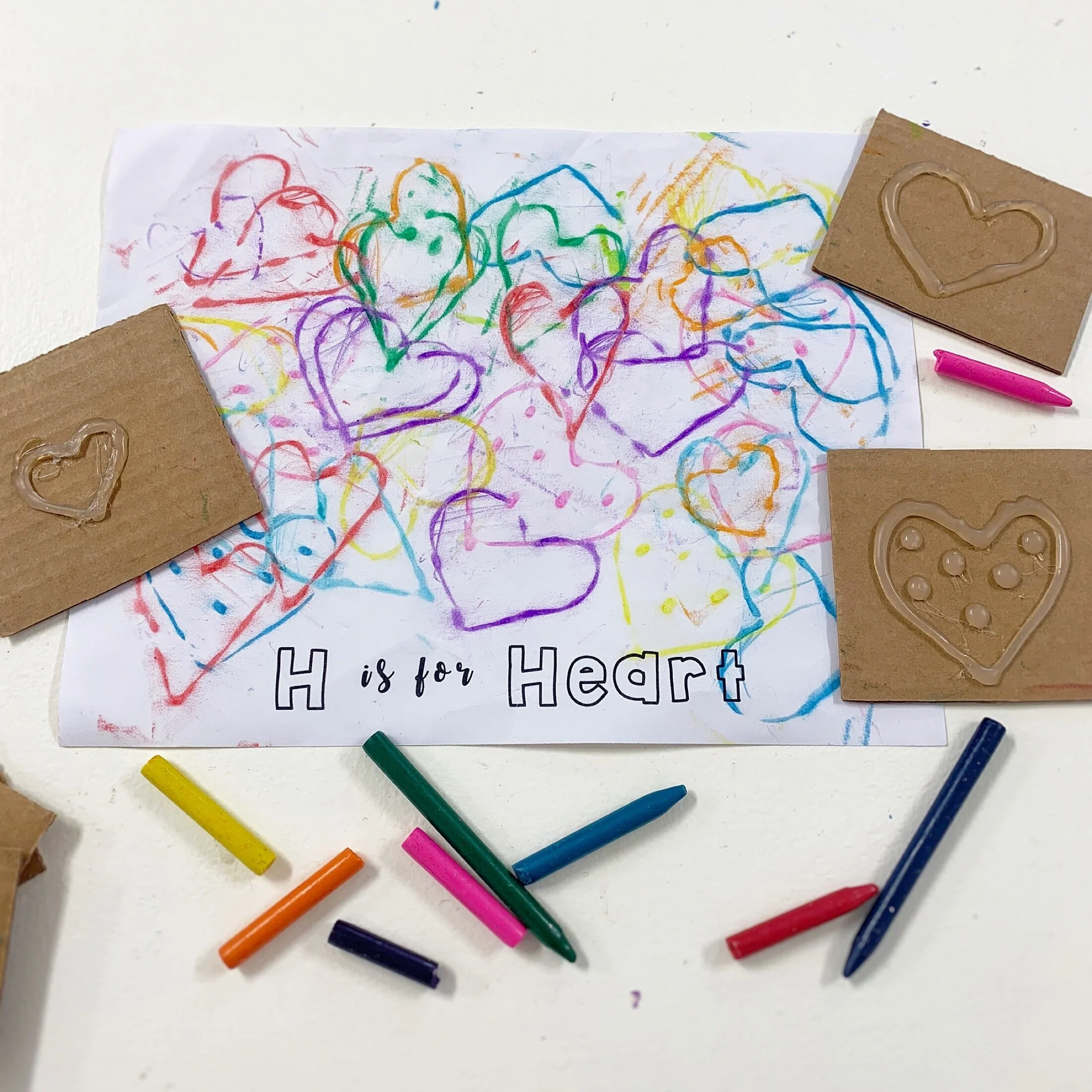 Use hot glue to make heart shapes/designs on 2 inch-ish cardboard squares. Be generous with the hot glue, the more raised the shape is, the more defined the lines will be as they show up on the paper. Once the glue has dried, place the cardboard squ…