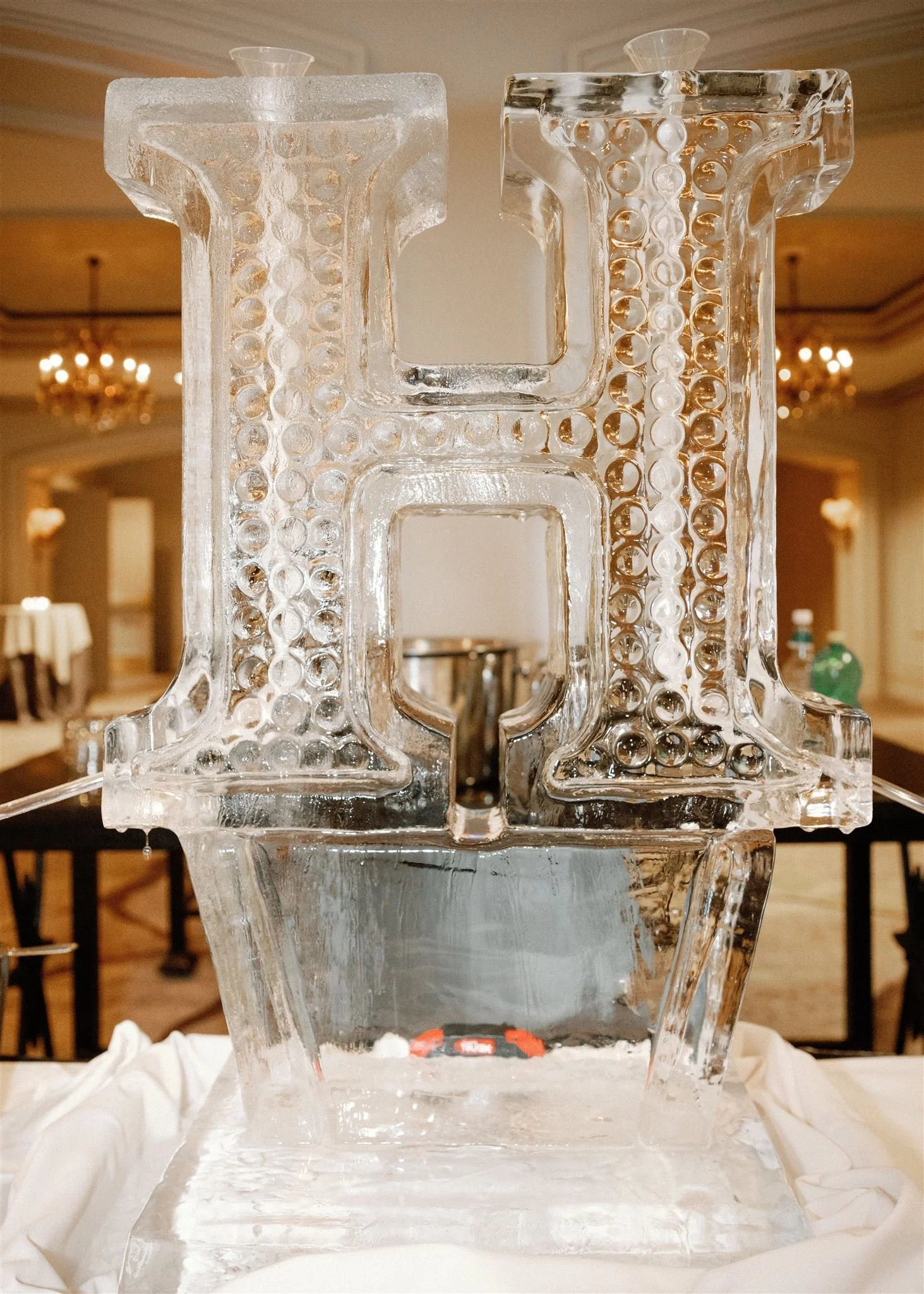 Close-up of an ice sculpture with intricate patterns, placed on a table in a decorated interior setting.
