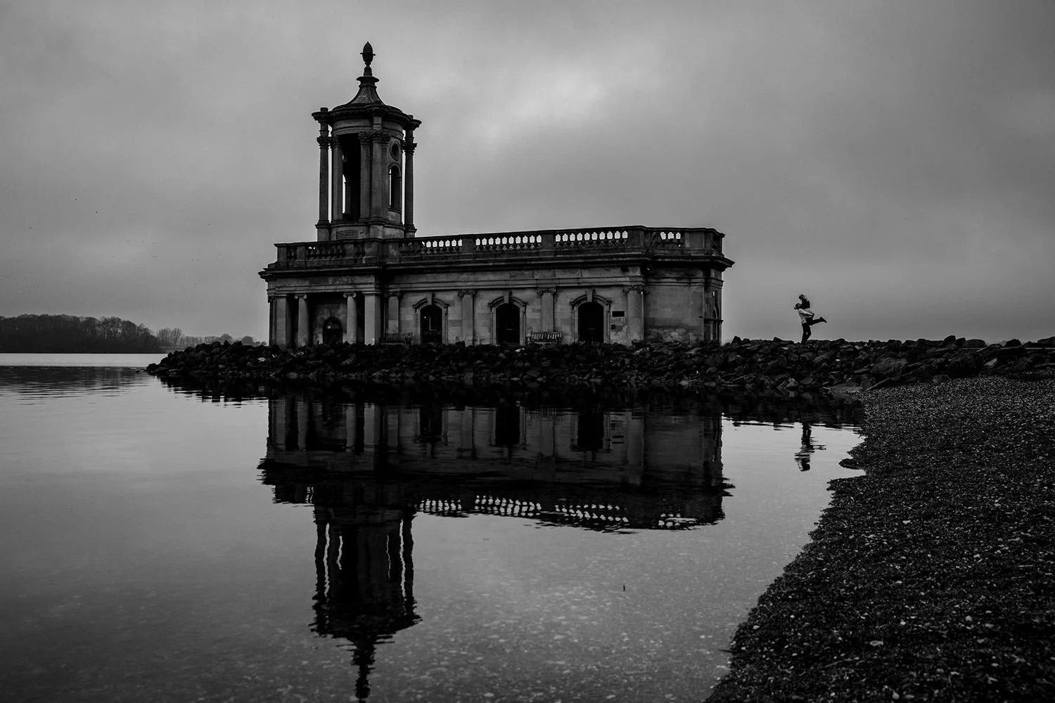 A black and white Engagement photos at Normanton Church with groom lifting up bride in a silhouette