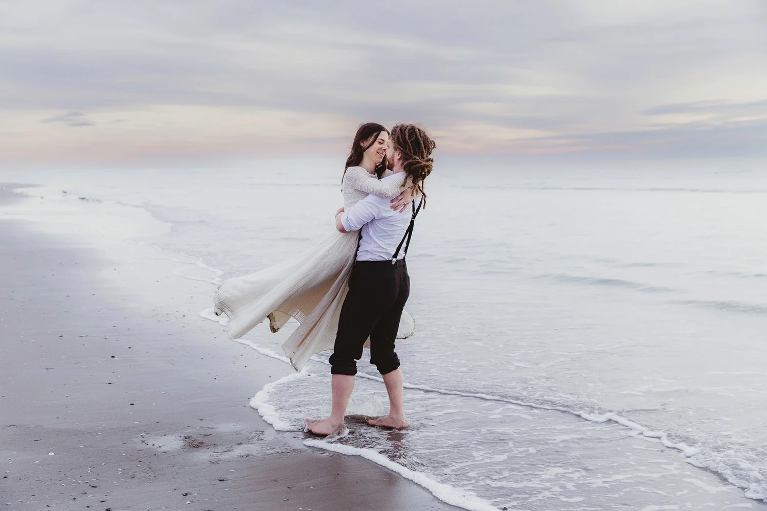 Groom picking up bride on the shoreline