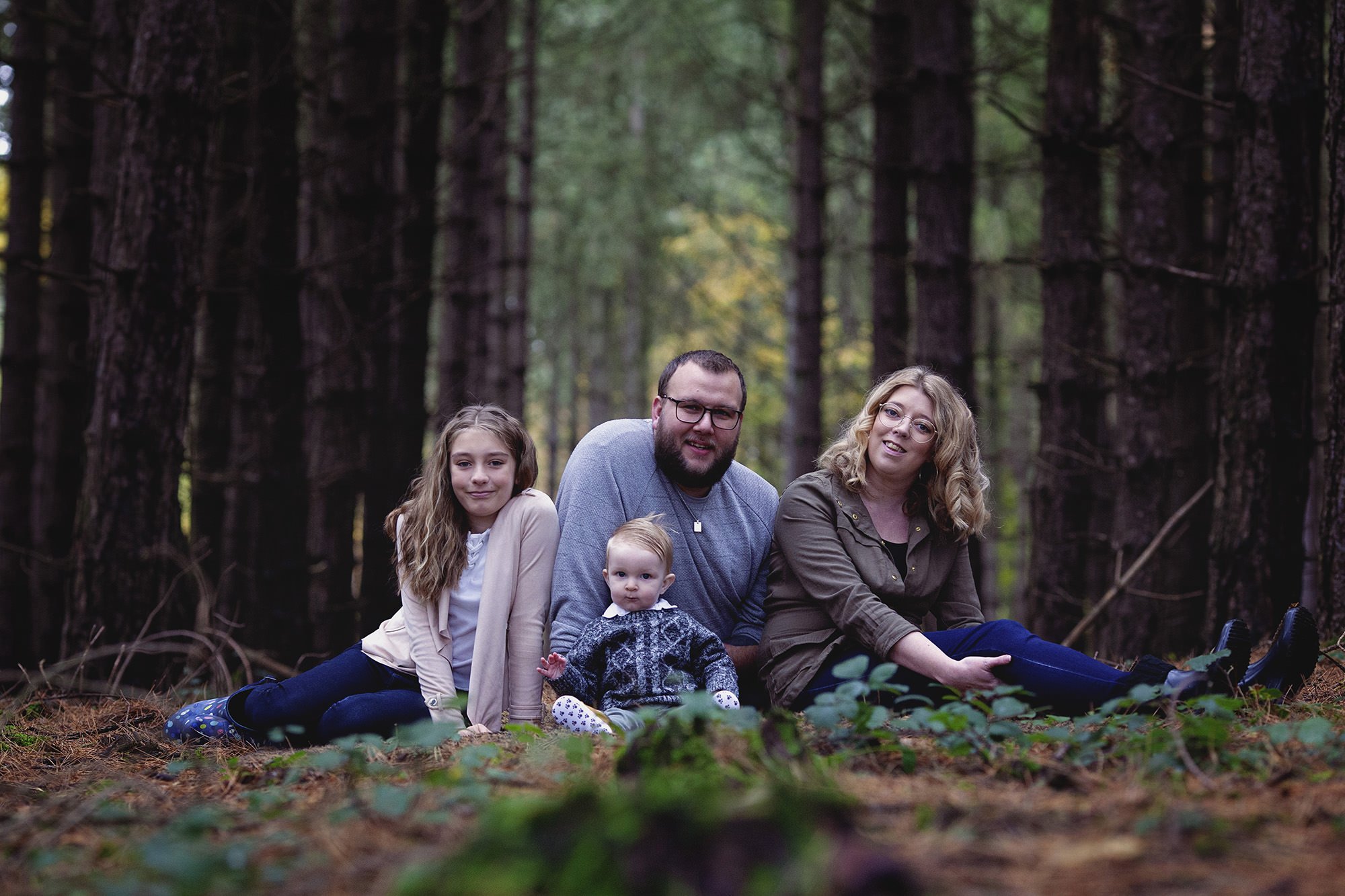 Family posing in conifer wood