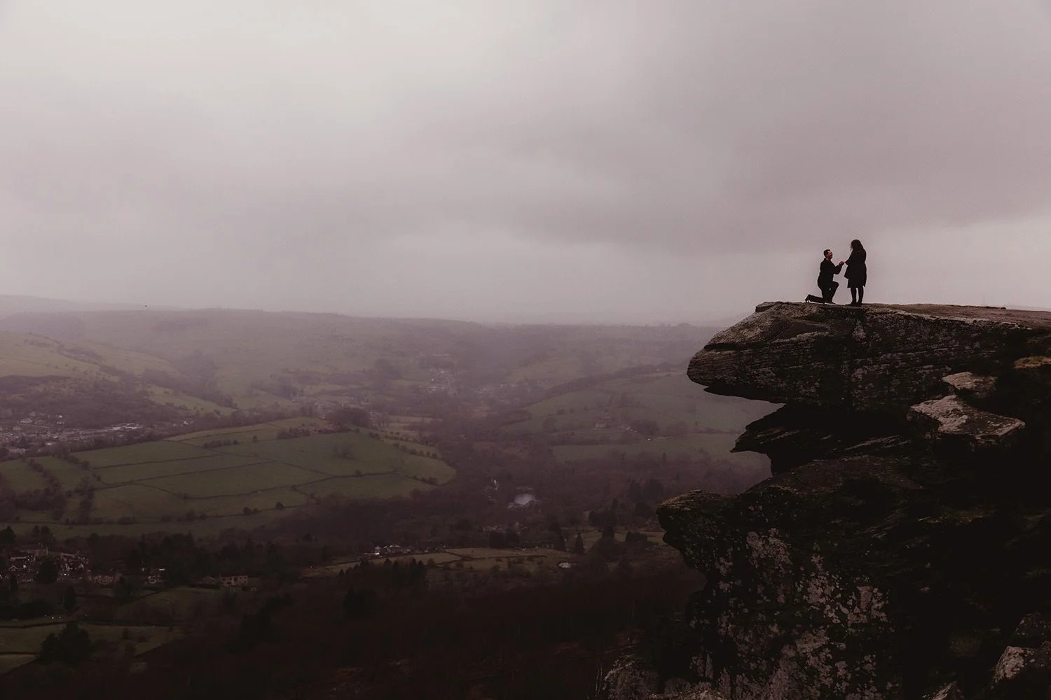 Engagement photos of aa man proposing to woman on top of Curbar Edge in Peak District