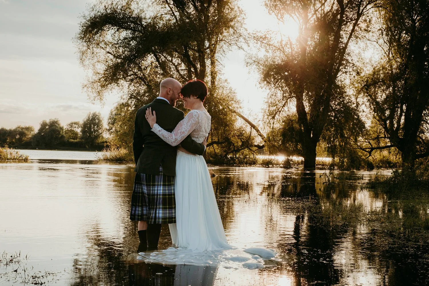 Bride and groom standing by a loch