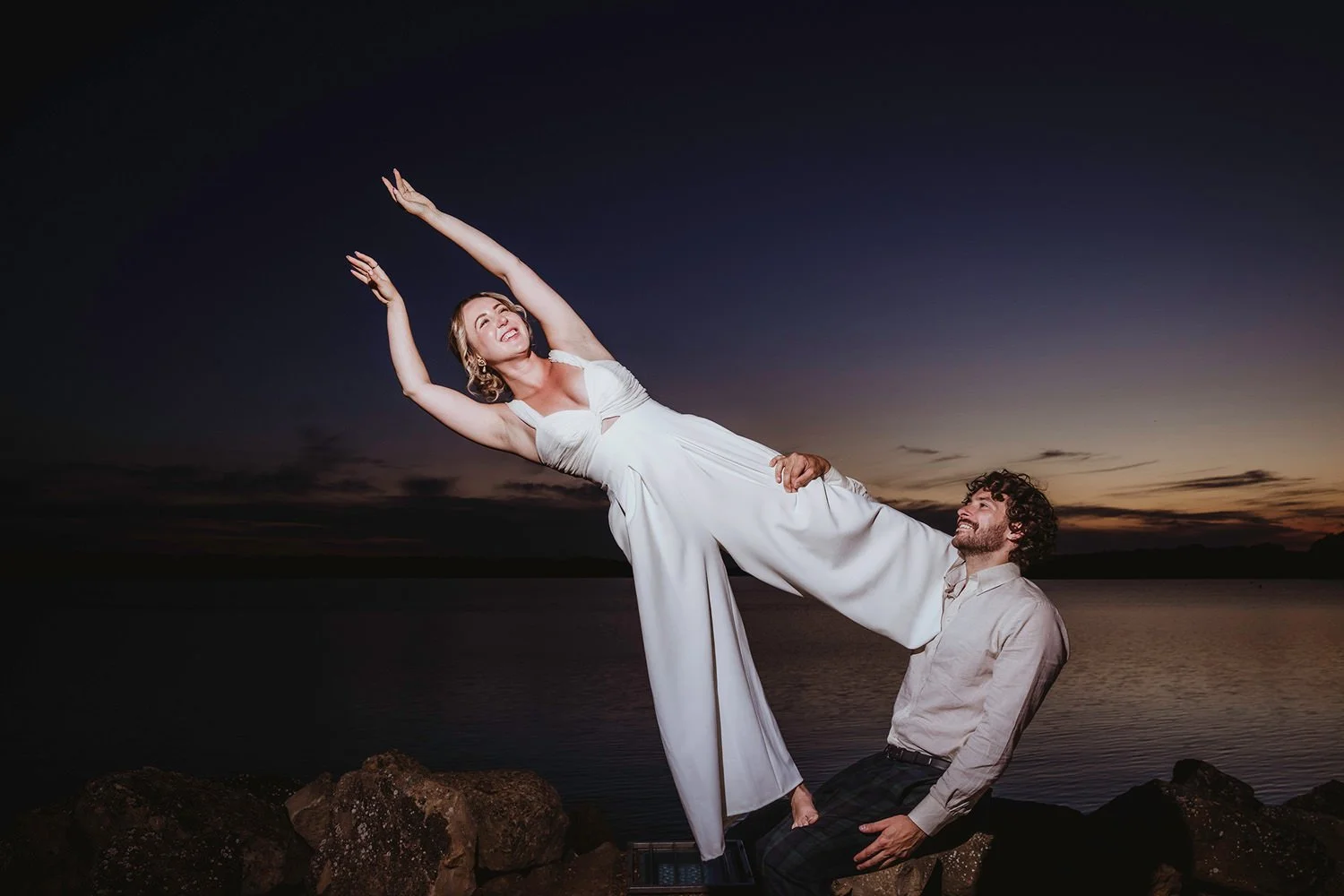 Bride and groom doing acro-yoga at twilight