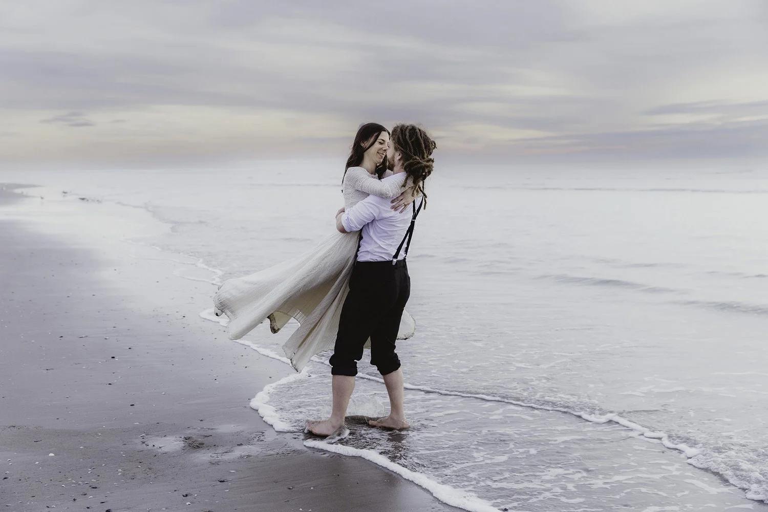 groom carrying bride on the beach