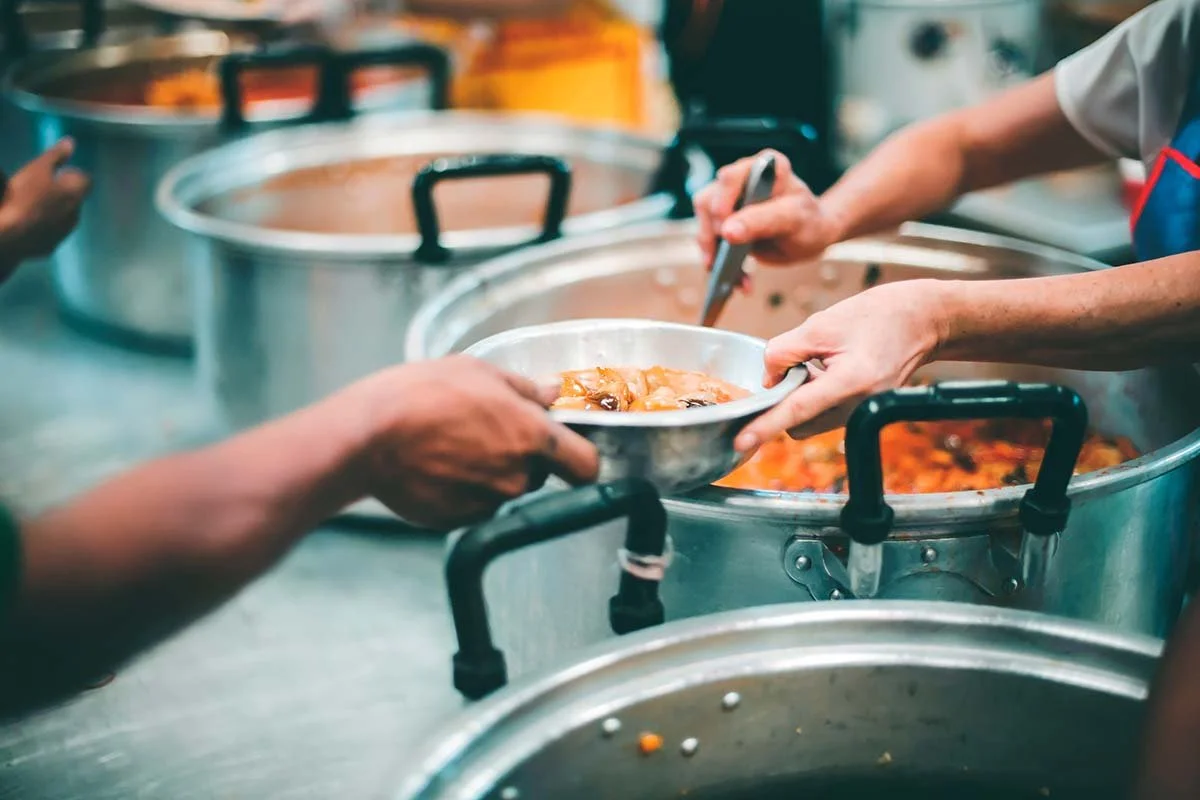 Photo of people being fed in a soup kitchen to symbolize the concepts in our article, "Interpreting Generously: Seeing Our Shared Humanity."