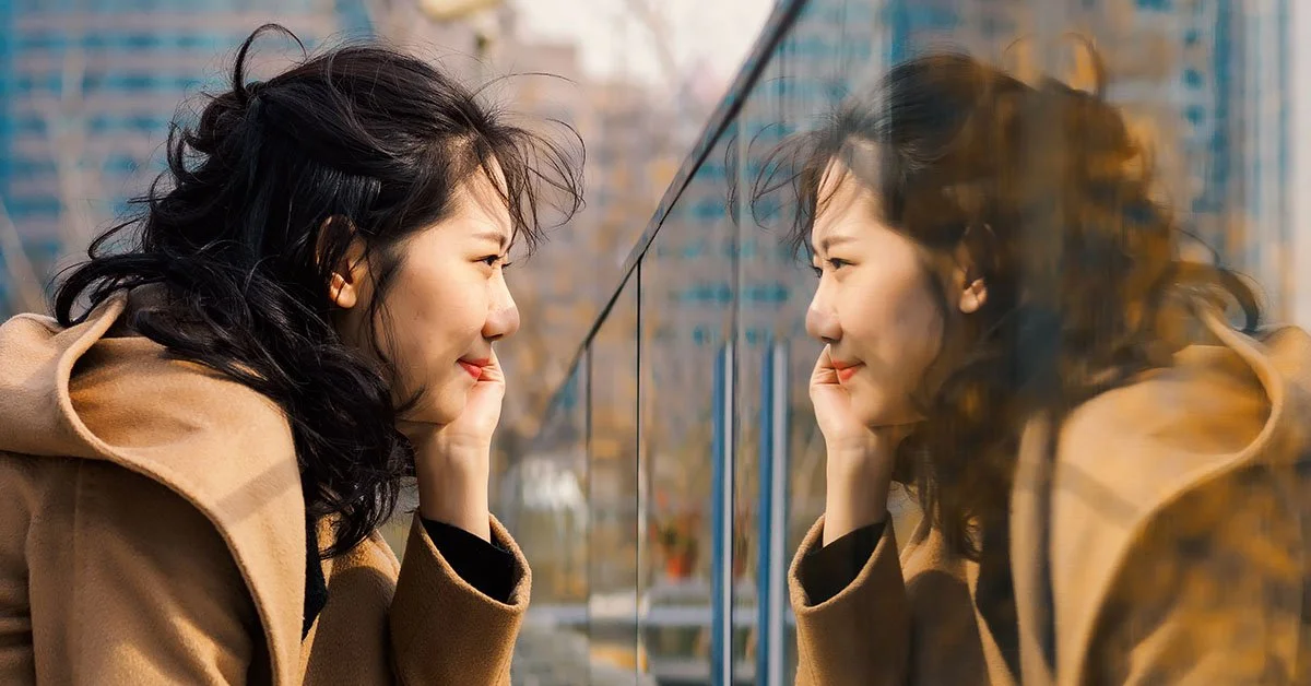 Image of woman looking at her own reflection to demonstrate "Strengthening Self-Compassion and Inner Capacity" for the Center for Compassionate Leadership blog post, "How To Apply Compassionate Leadership."