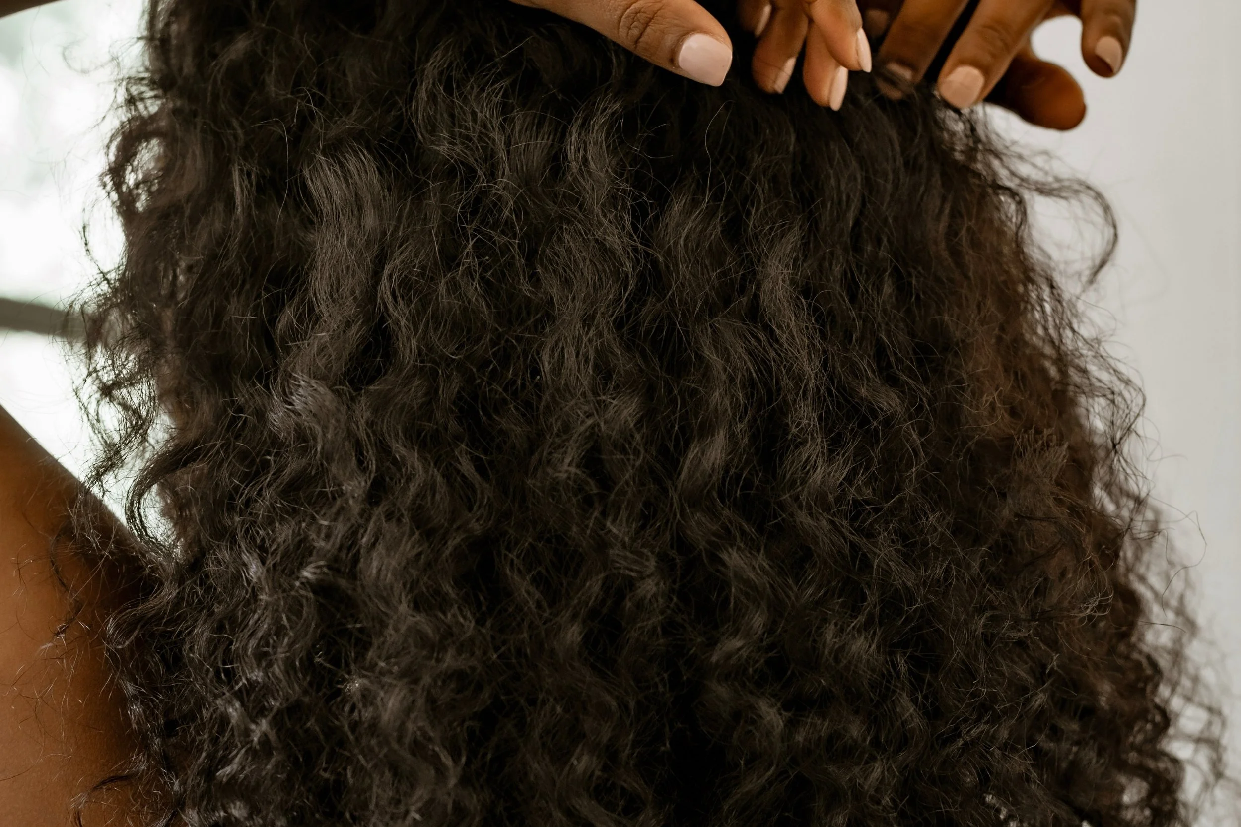A woman with naturally defined curls showing the result of a texture-appropriate dry haircut at Ergun Tercan European Salon in Denver.