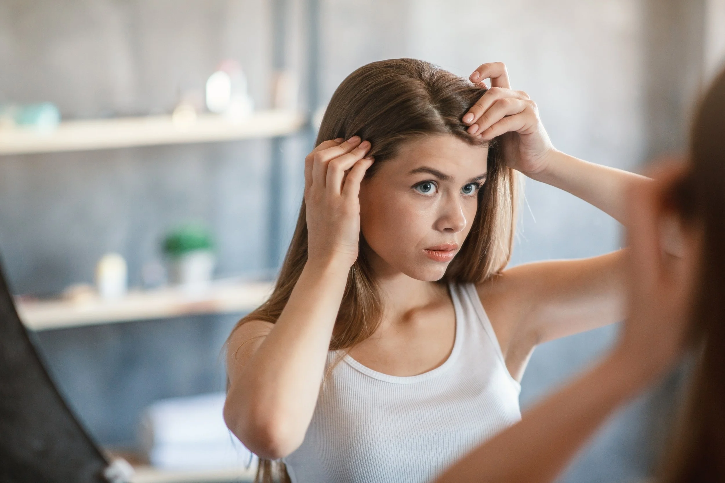 postpartum hair changes woman looking in mirror
