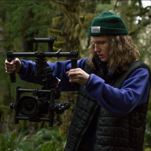 Person operating camera stabilizer outdoors in a forested area