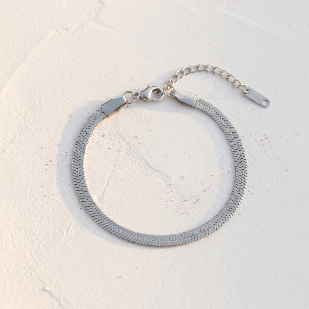 Slim silver herringbone chain bracelet on white cracked surface - stainless steel jewellery London - Kincha Designs