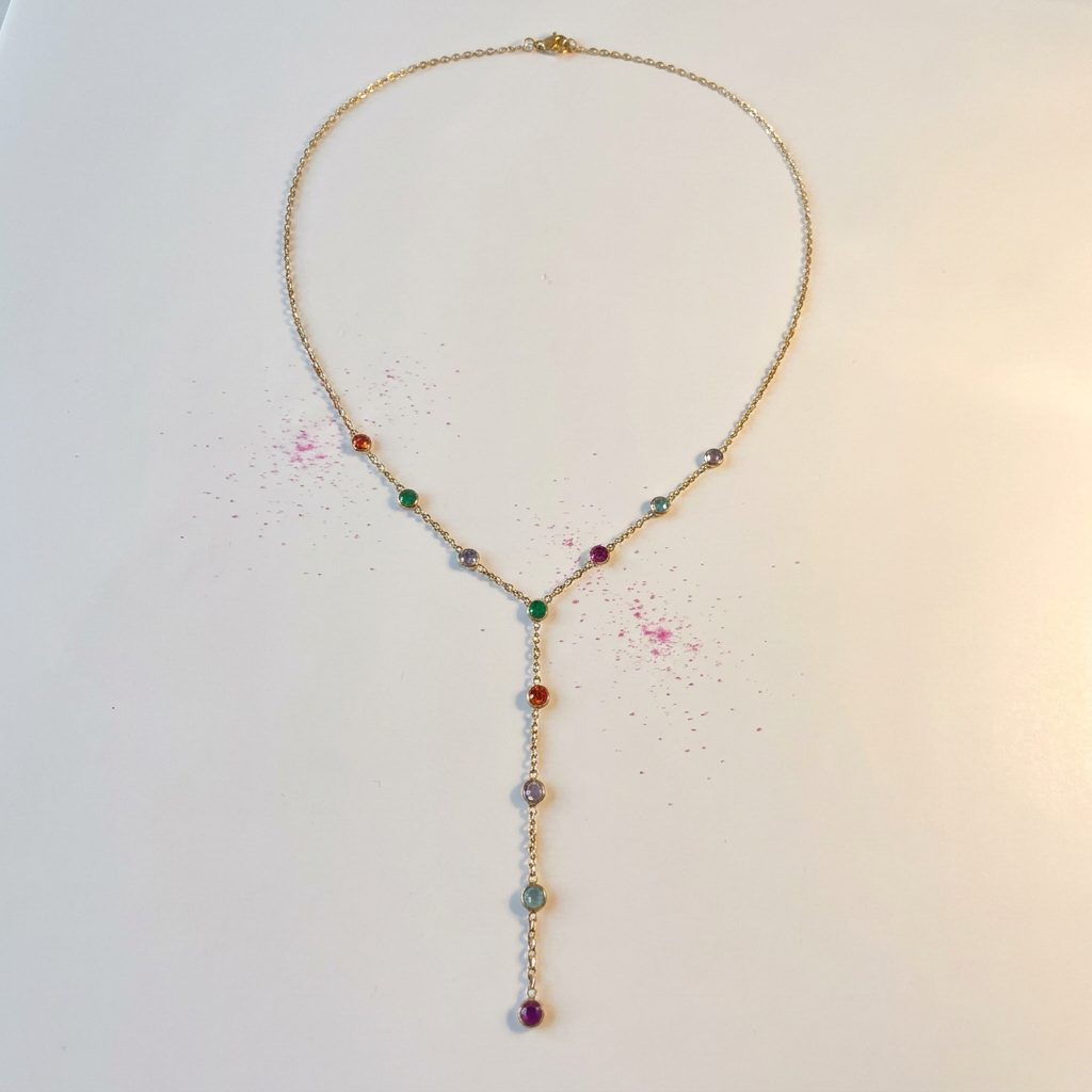 Gold rainbow crystal lariat necklace on white surface with fuchsia pink splash - stainless steel jewellery London - Kincha Designs