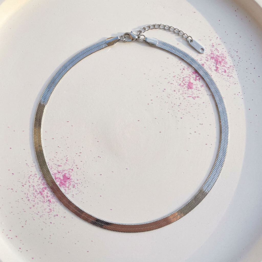 Slim silver herringbone chain necklace on white surface with fuchsia pink powder - stainless steel jewellery London - Kincha Designs