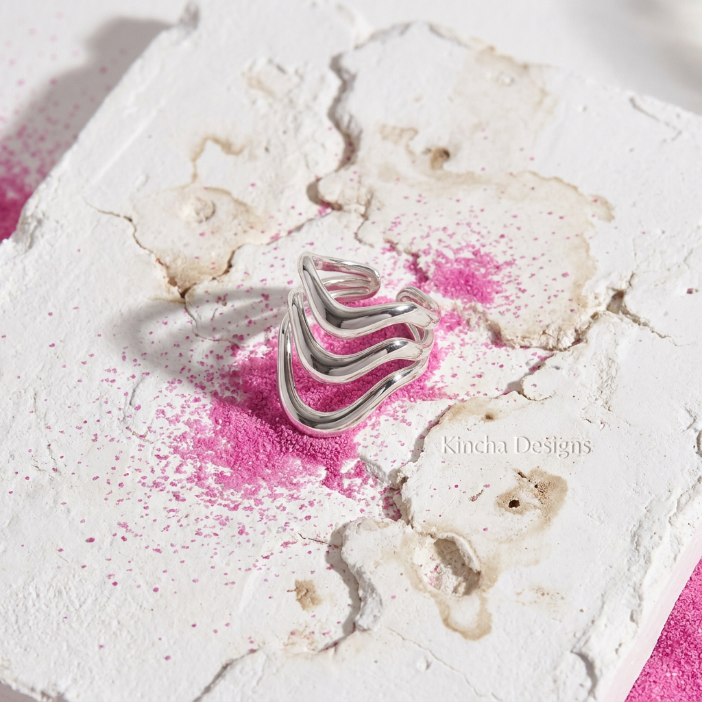 Silver wave ring on cracked white concrete with fuchsia pink sand - stainless steel jewellery London - Kincha Designs