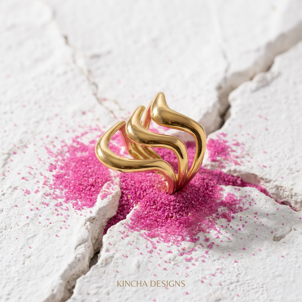 Gold wave ring on cracked white concrete with fuchsia pink sand - stainless steel jewellery London - Kincha Designs
