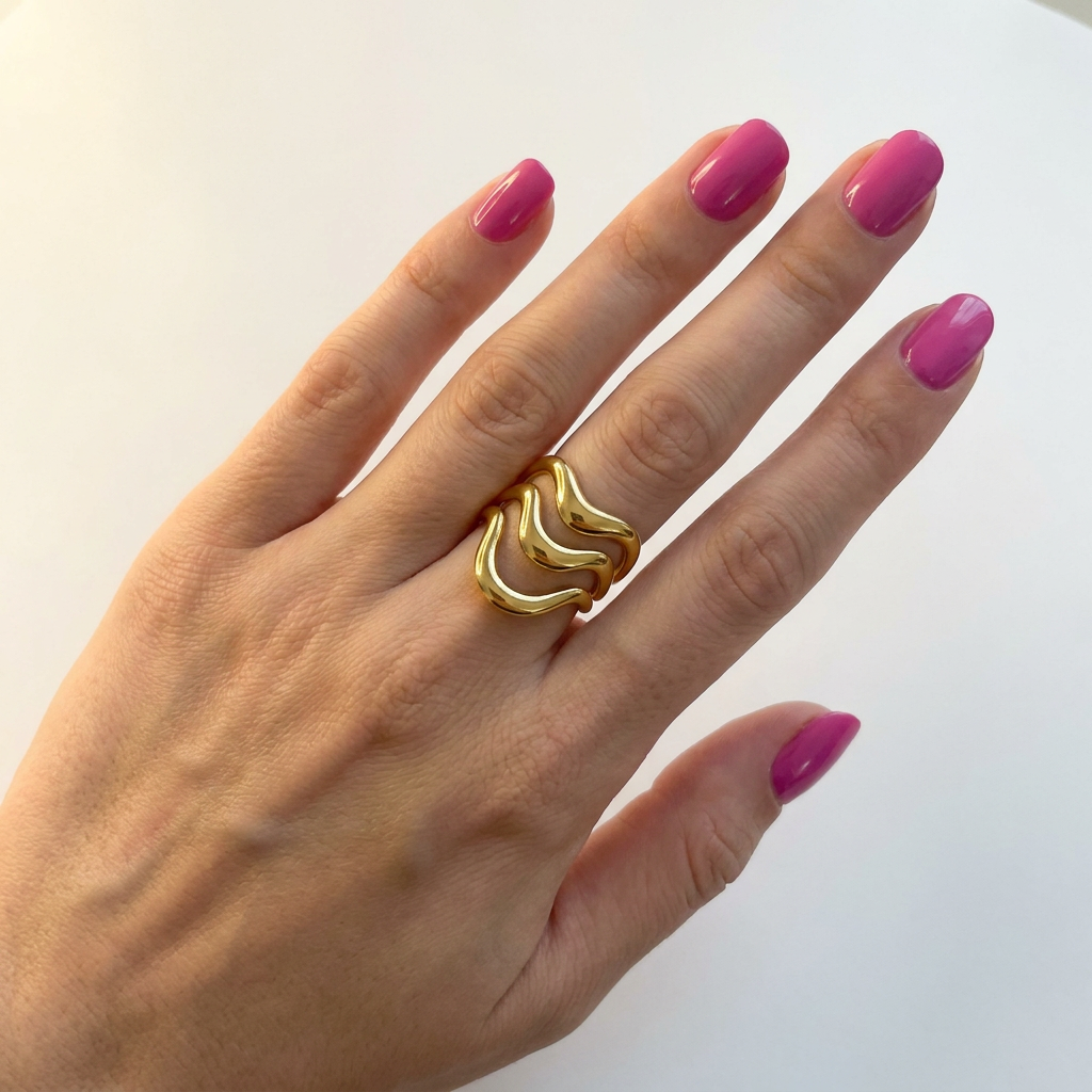 Hand wearing gold wave stainless steel ring with pink nails - statement jewellery - Kincha Designs London