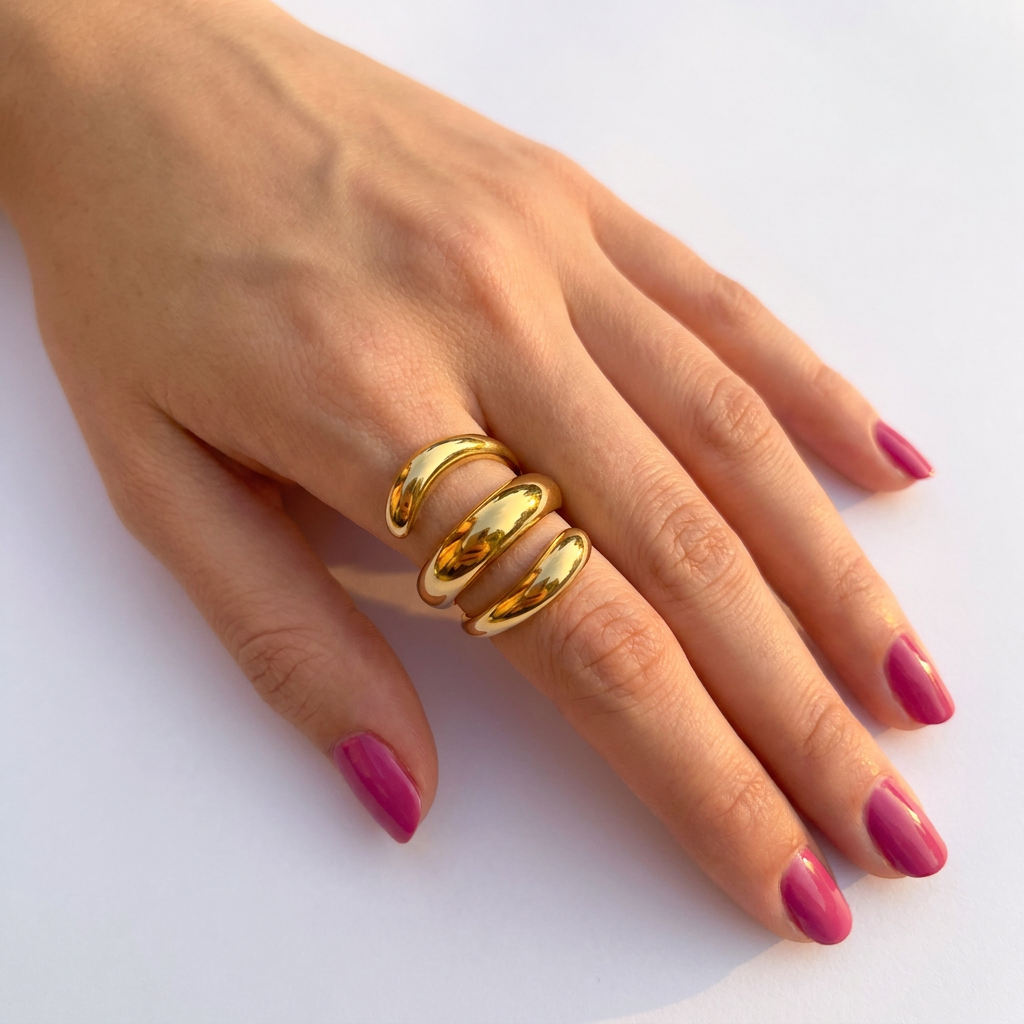 Hand wearing gold triple coil stainless steel ring with pink nails - statement jewellery - Kincha Designs London