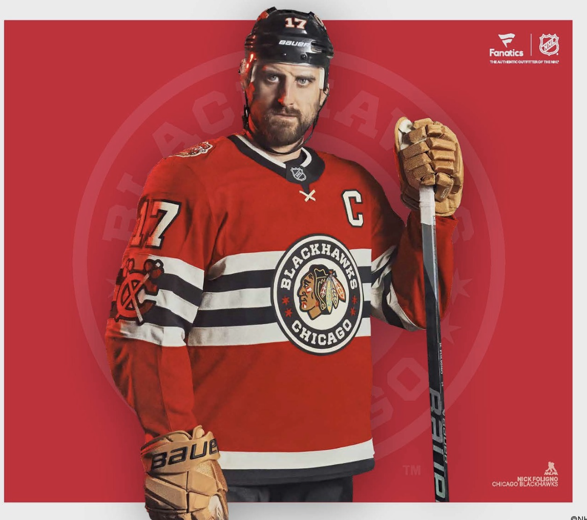 A man wearing a Chicago Blackhawks hockey jersey, helmet, and gloves, holding a hockey stick, standing in front of a red background with team and league logos.