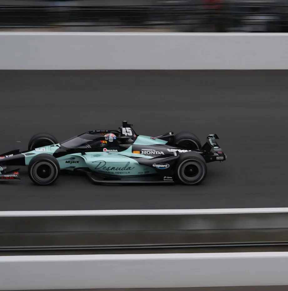 A race car driving on a track with a blurred background.