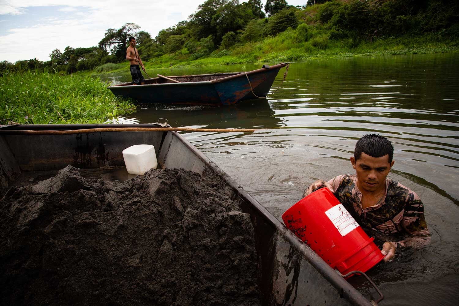   Luis Jarquin goes under water with a bucket to collect sand and throw it into his boat. Tempisque sand excavators have been working in the same way since the middle of the last century.  