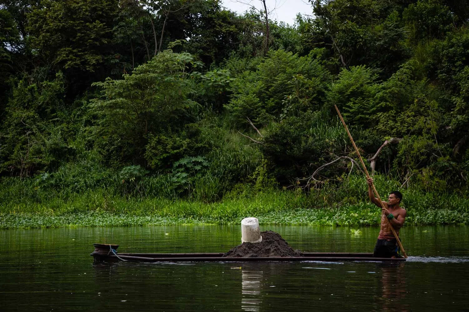   Byron moves his panga downstream to unload it. Laborers like him earn between ¢3,500 and ¢5,000 (about $5.80 to $8.50) for each boat filled with sand, depending on the size of the boat.  