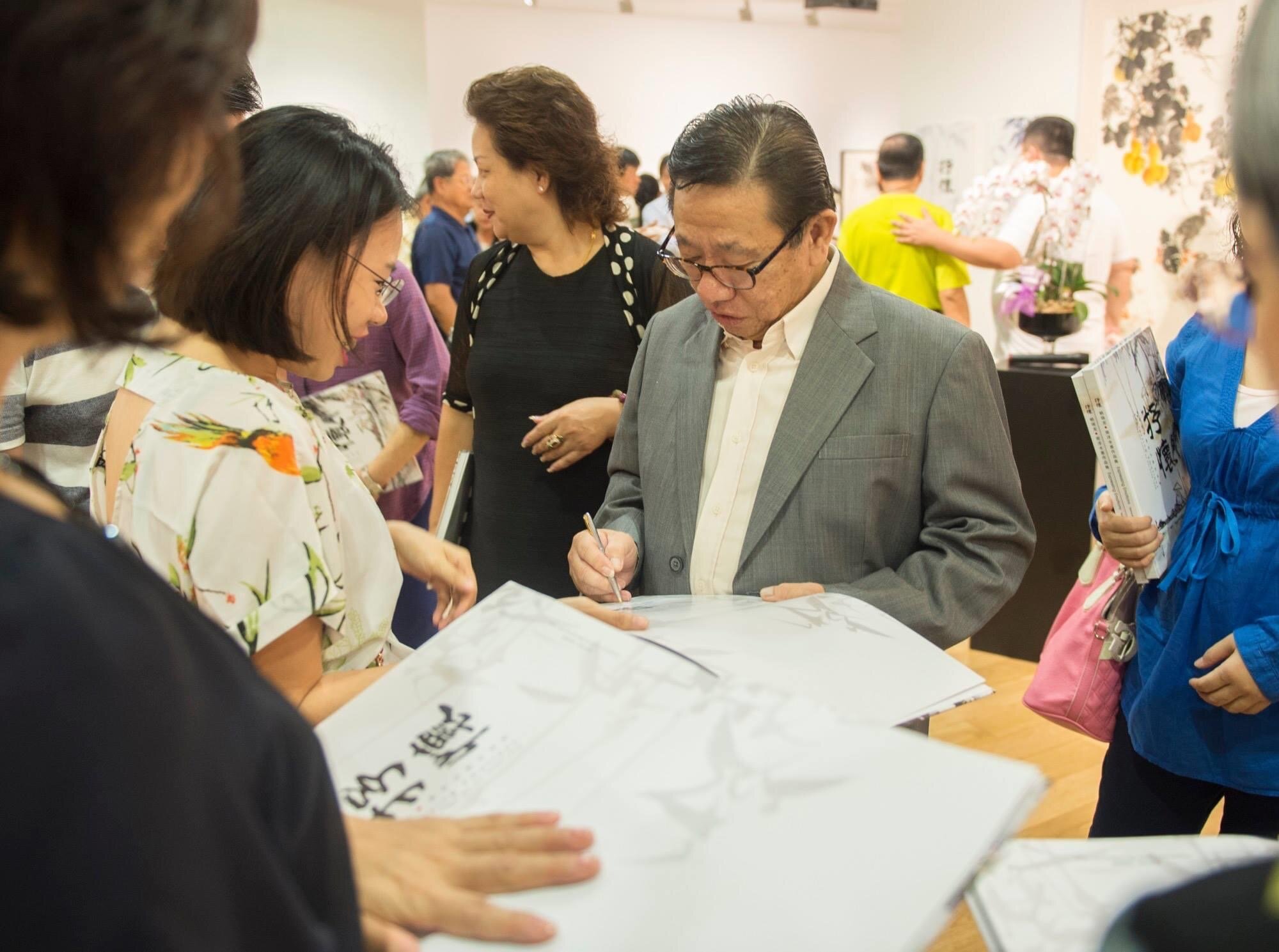  Mr Nai Swee Leng signing on his art catalogues for guests during his solo exhibition in 2016  