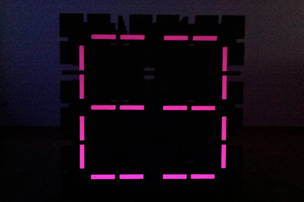 Black modular sculpture forming a large, digital ‘8’ built from stick together wooden elements.