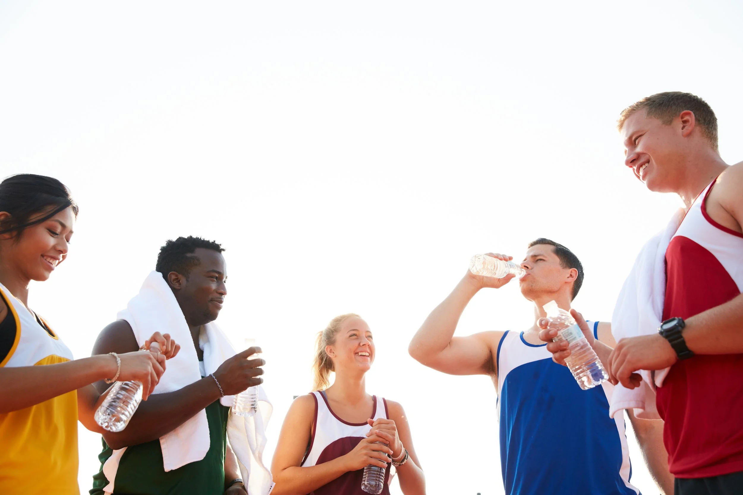 Diverse group of runners smiling and hydrating together after a workout, representing fellowship, accountability, and Christian community.