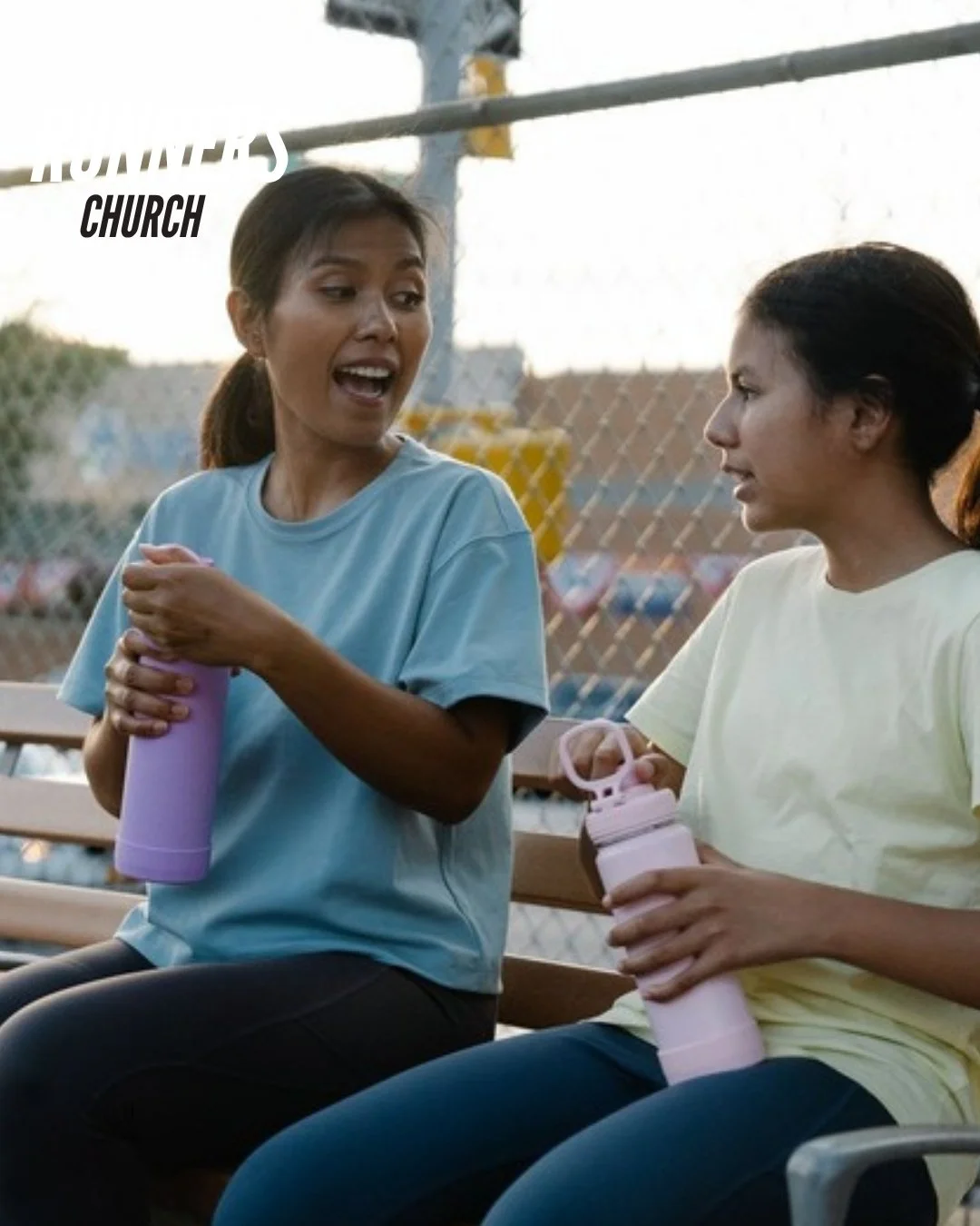 Two women pausing on a park bench in conversation, one leaning in to listen while the other speaks, representing intentional availability, humble service, and the witness of showing up for others.