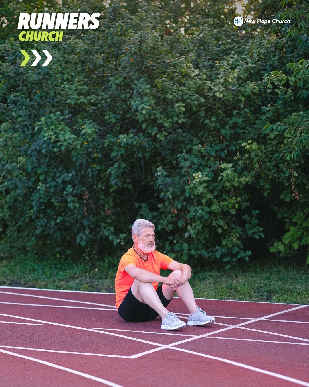A man sitting alone on a running track, knee drawn up, looking into the distance in quiet thought