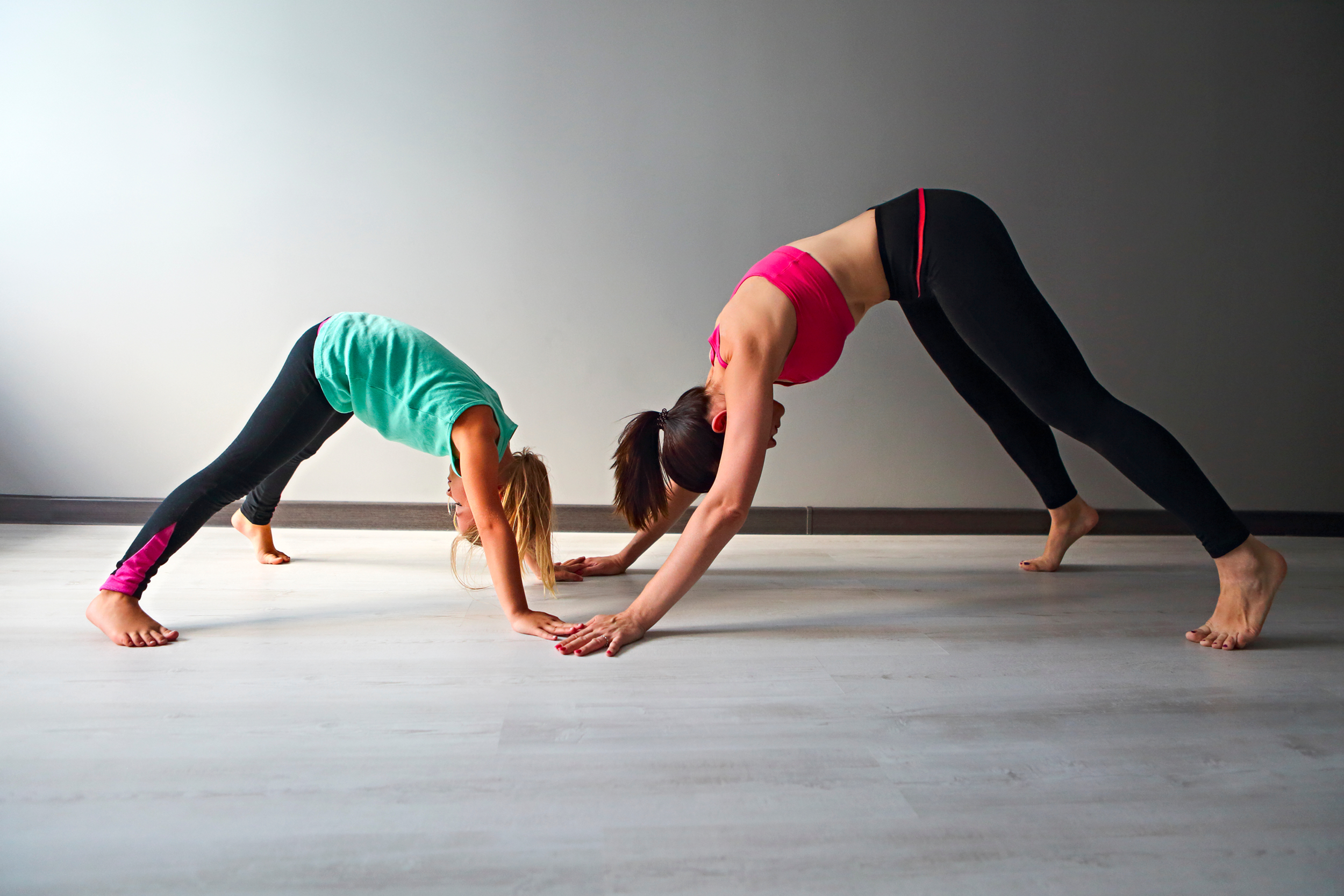 Canva - Young woman having fun with kid doing yoga.png